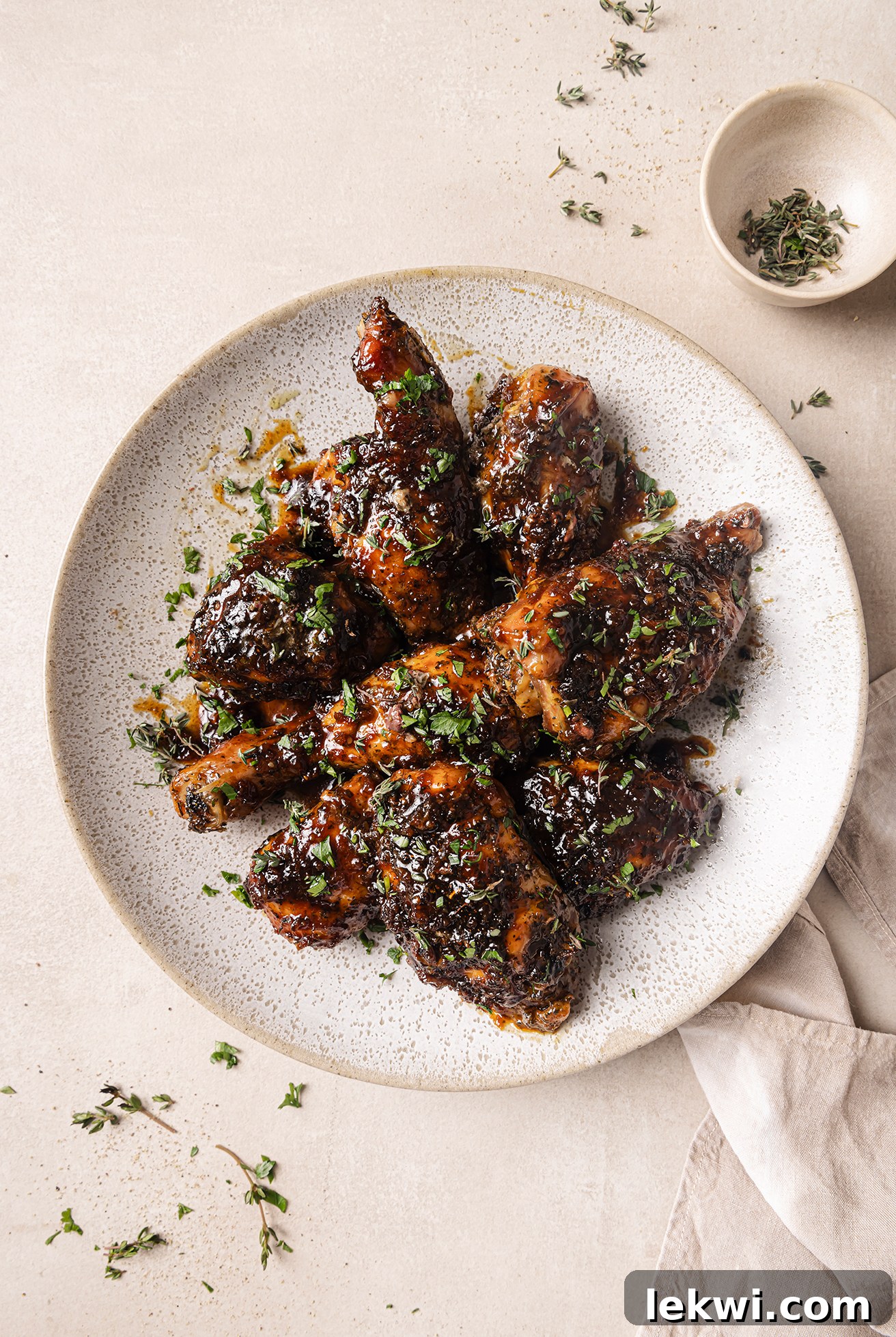 A plate of perfectly baked and glazed turkey wings, garnished with fresh thyme leaves.