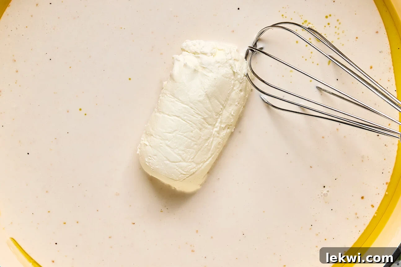 Goat cheese being mixed into a coconut milk mixture with a whisk.