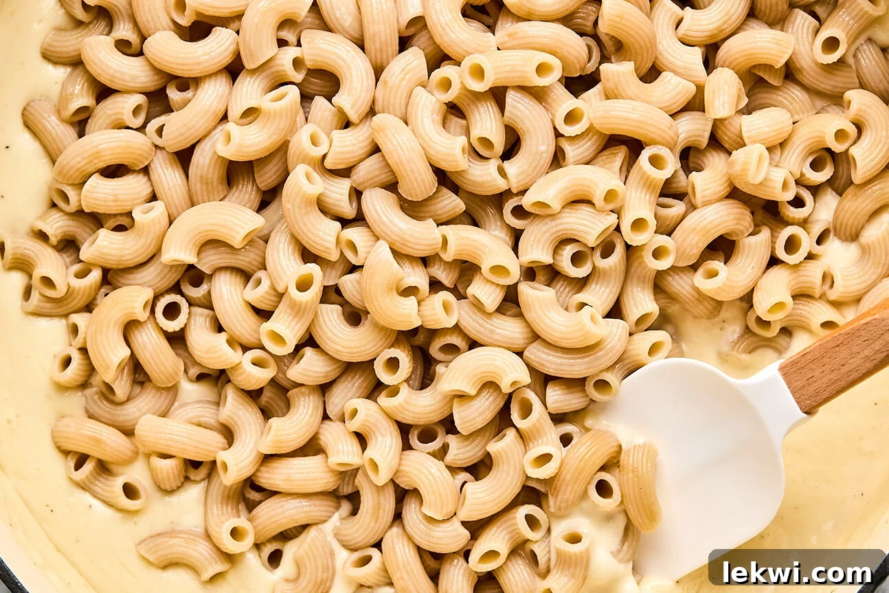 A bowl with goat cheese sauce under cooked pasta.