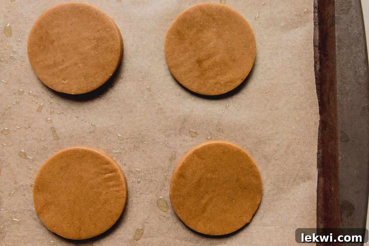 Raw gingerbread cookies placed on a baking sheet lined with parchment paper.