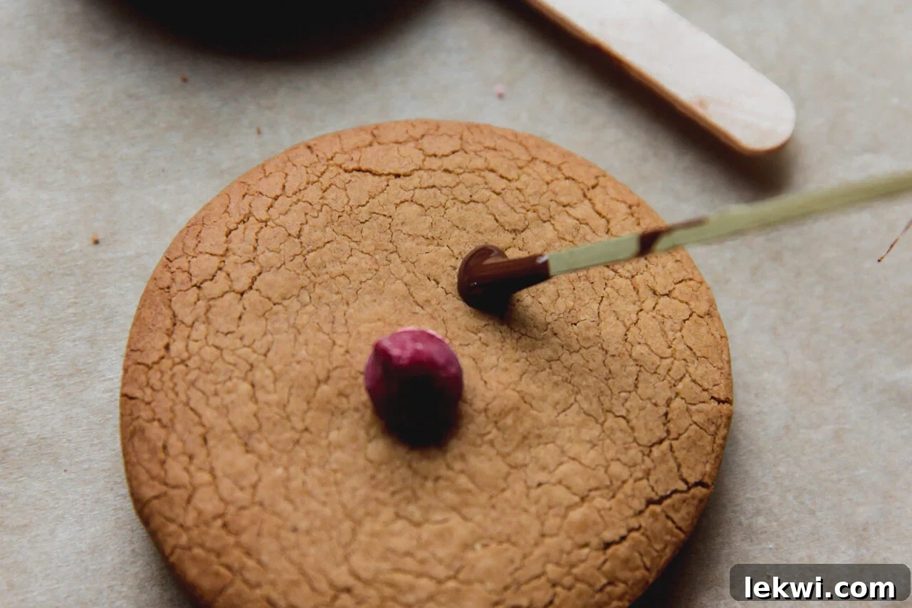 Decorating gingerbread cookies with a red nose and drawing antlers with melted chocolate.