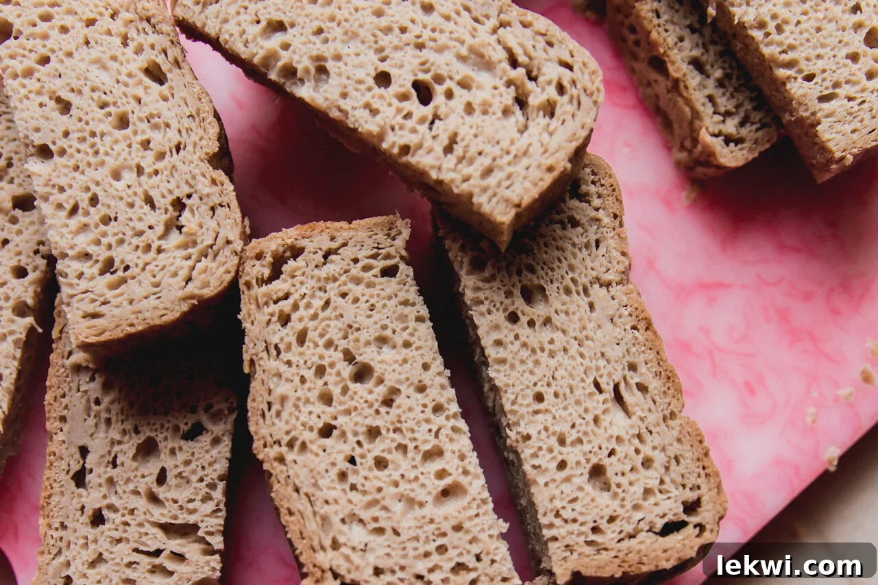 Gluten-free bread slices neatly stacked on a wooden cutting board, ready for preparation.