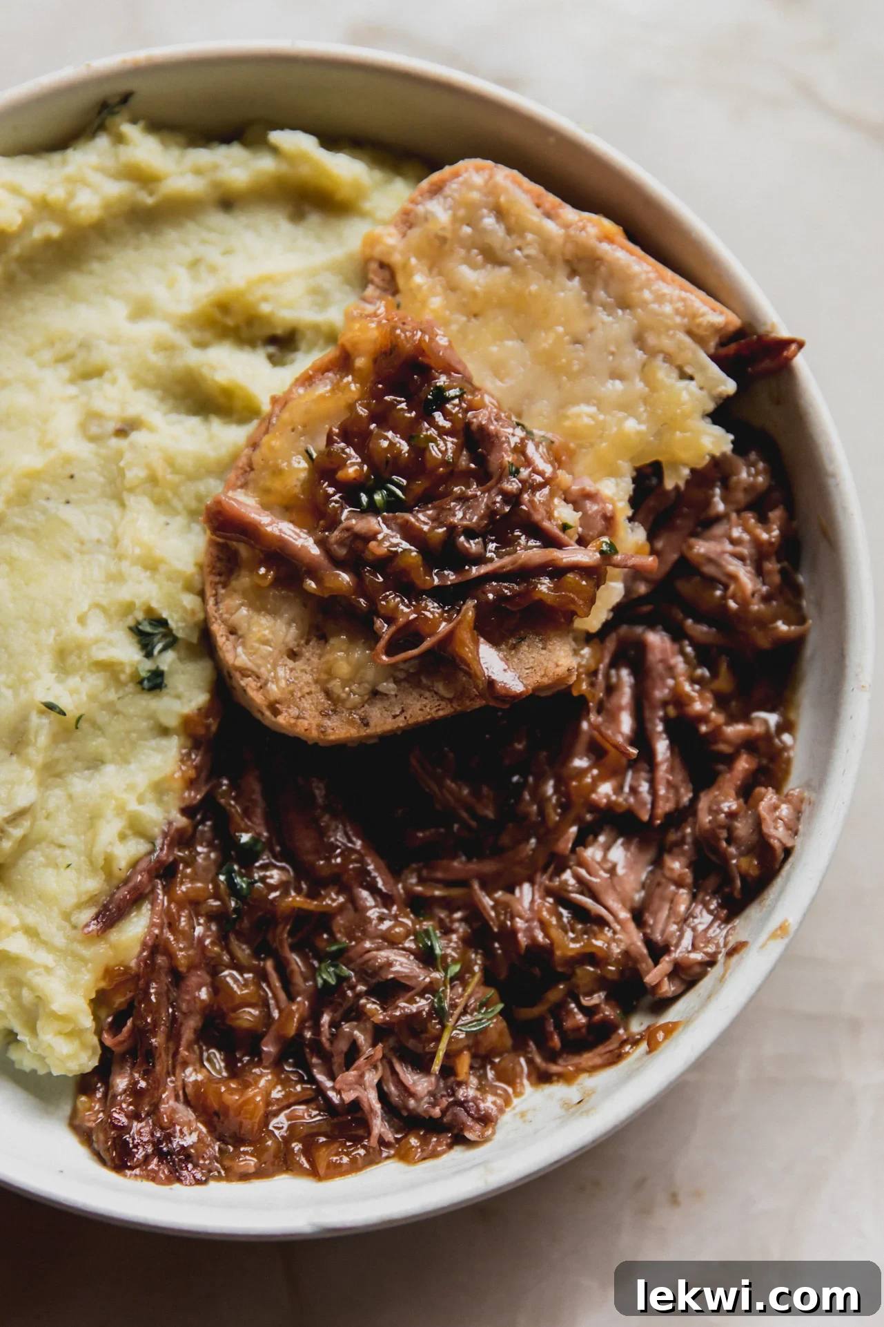 French onion pot roast with a piece of toast topped with some roast. 