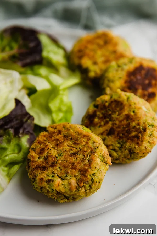 Three perfectly baked salmon cakes stacked on a white plate, ready for a healthy and satisfying meal.