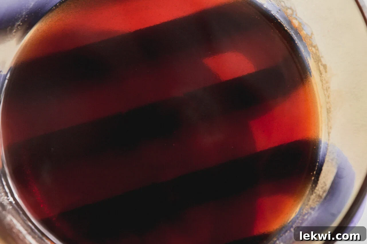 The gumdrop mixture is depicted in a pot on the stove after being gently heated, showing it has transformed back into a smooth, clear liquid, ready for molding.