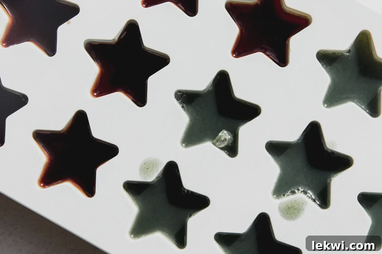 Vibrant gumdrops in various shades, freshly poured into a star-shaped silicone mold, are shown in the process of setting, ready for refrigeration.