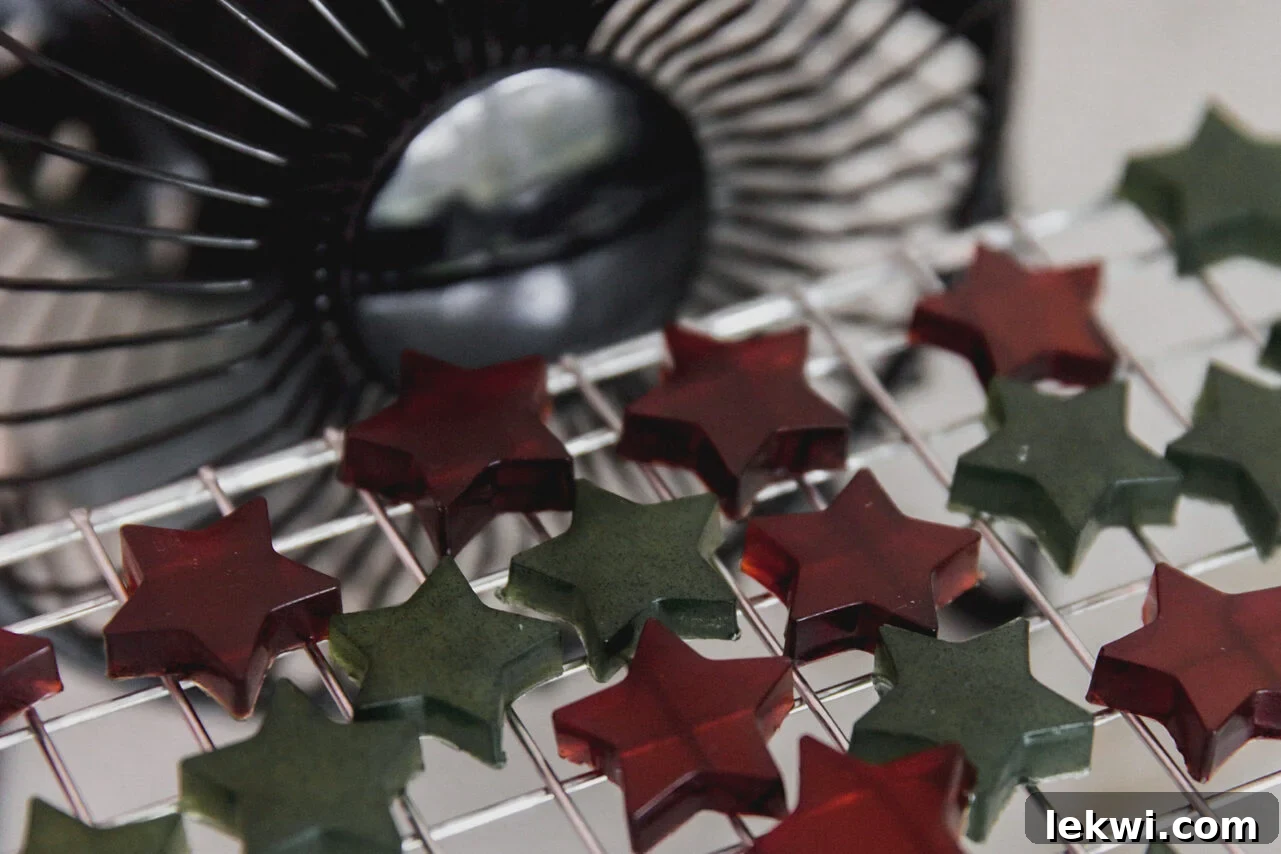 Set gumdrops, carefully removed from their molds, are placed on a wire rack elevated by glasses, with a small fan gently blowing air to aid in the essential drying process.