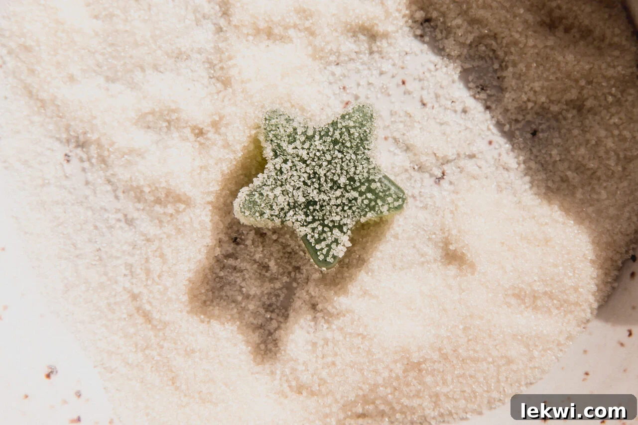 A vibrant green star-shaped gumdrop, now fully coated in granulated sweetener, rests in the bowl, glistening and ready to be enjoyed as a festive treat.