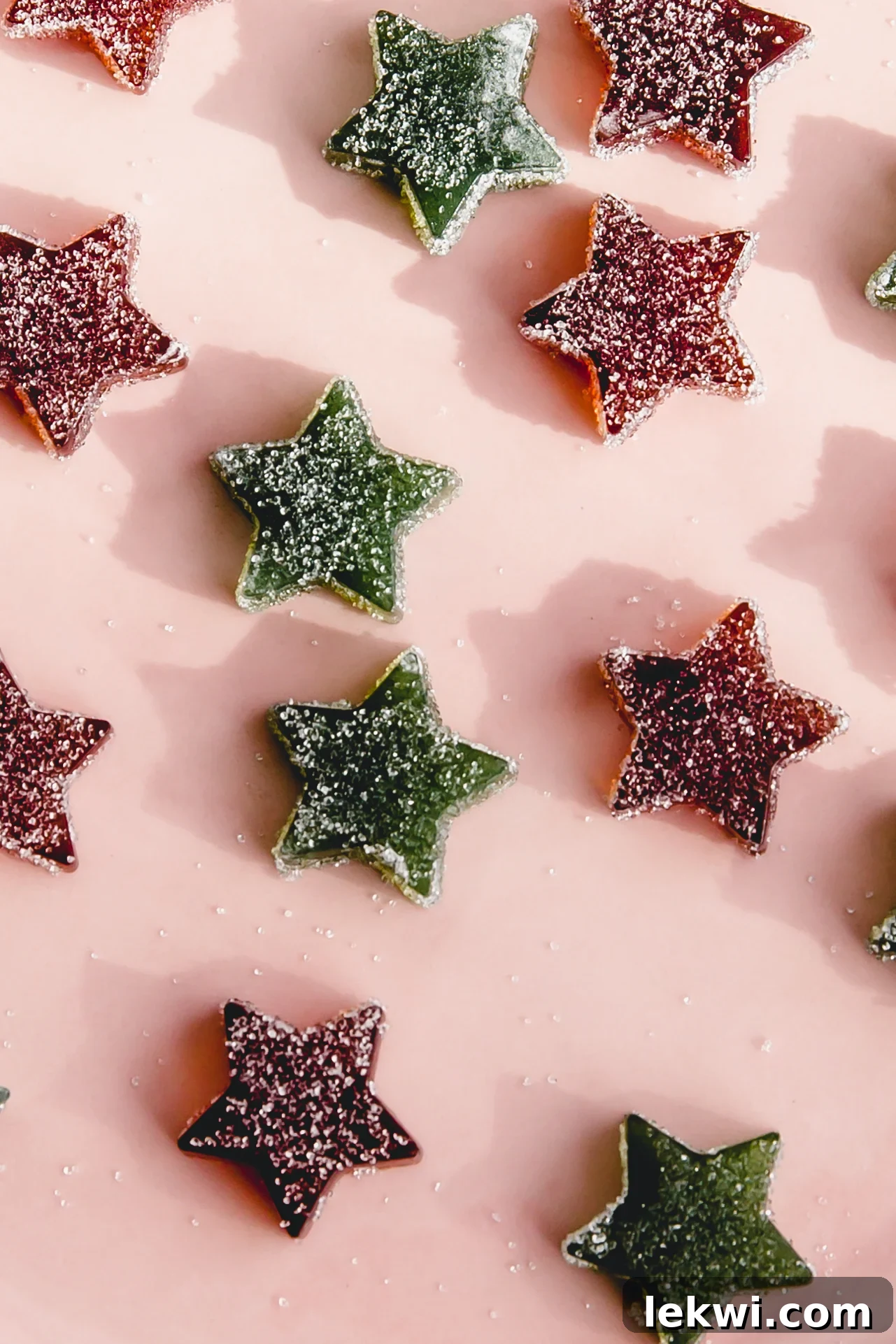 A collection of colorful star-shaped gumdrops, perfectly coated in glistening sugar, arranged on a delicate pink plate, ready to be enjoyed as a festive and sweet treat.