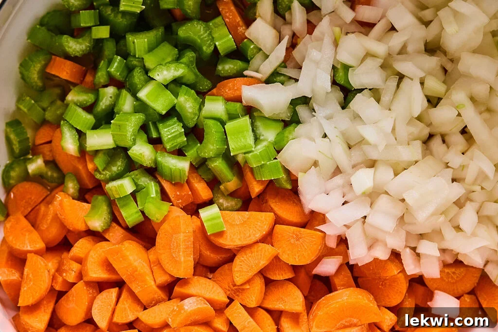 Finely chopped yellow onion, celery stalks, and carrots ready for sautéing in a large pot.