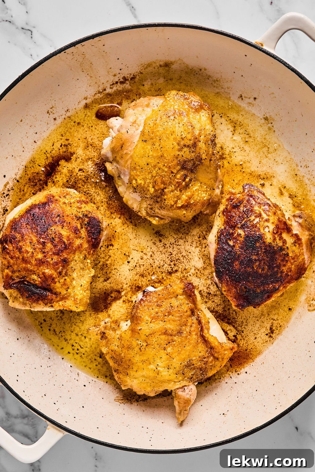 Chicken thighs after crisping in the pan, showing their golden brown color.