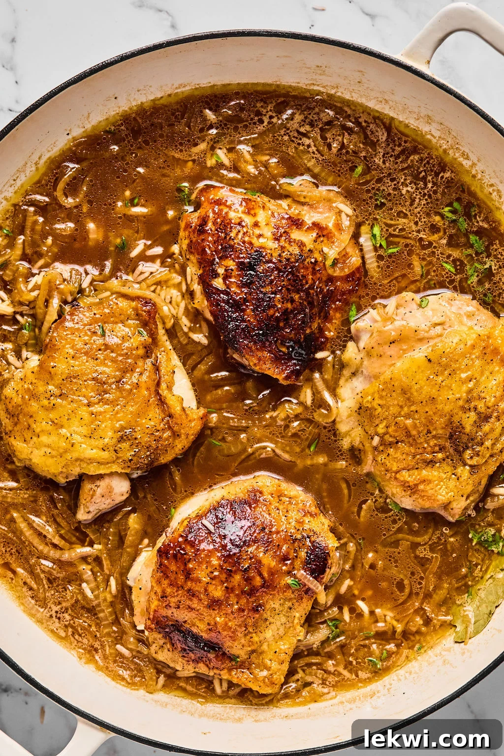 French onion chicken and rice after cooking, topped with melted cheese and fresh thyme, ready to be enjoyed.