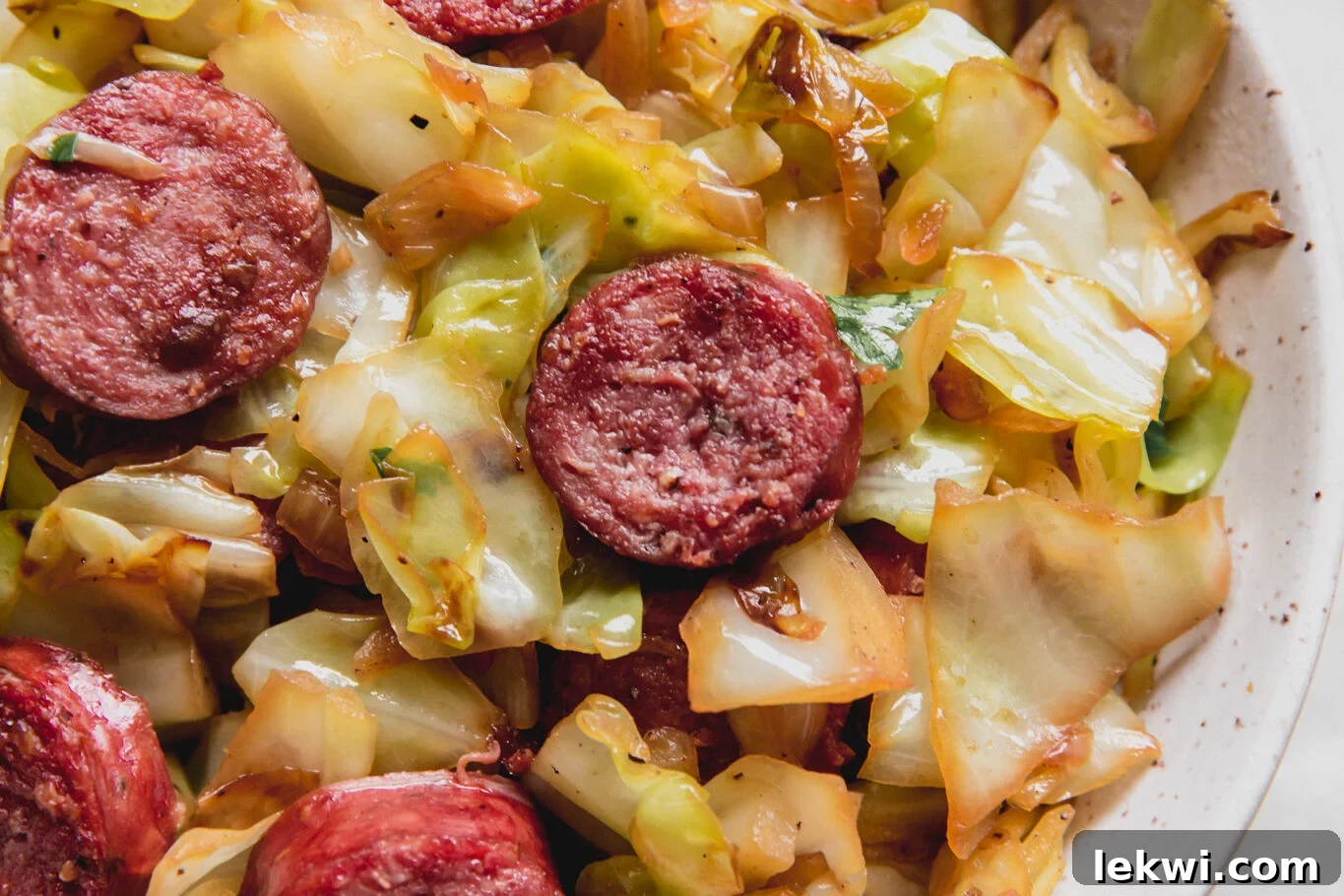 One-pan Southern Fried Cabbage & Sausage skillet, topped with fresh parsley.