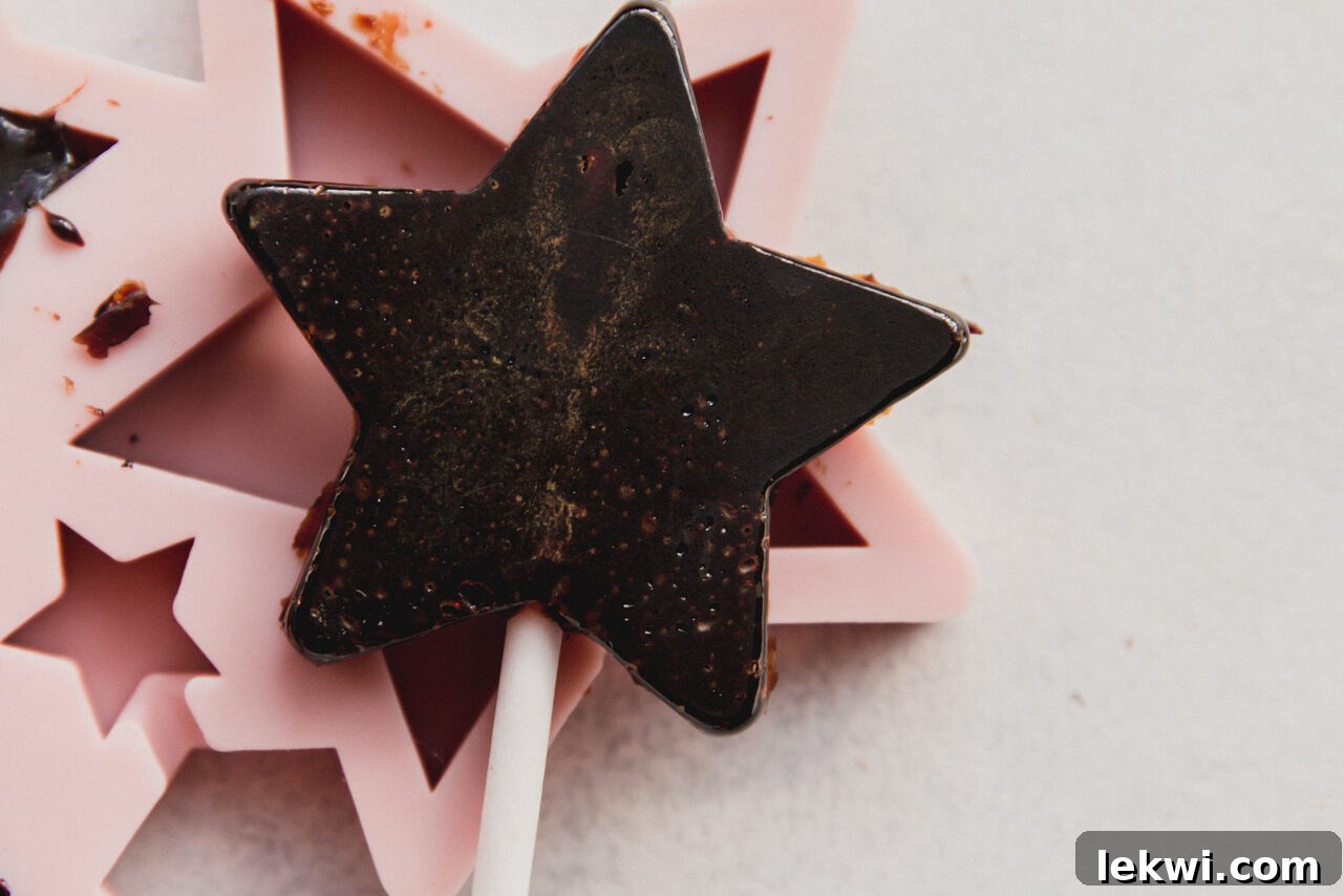 Finished star-shaped elderberry lollipops cooling and setting in a silicone mold.