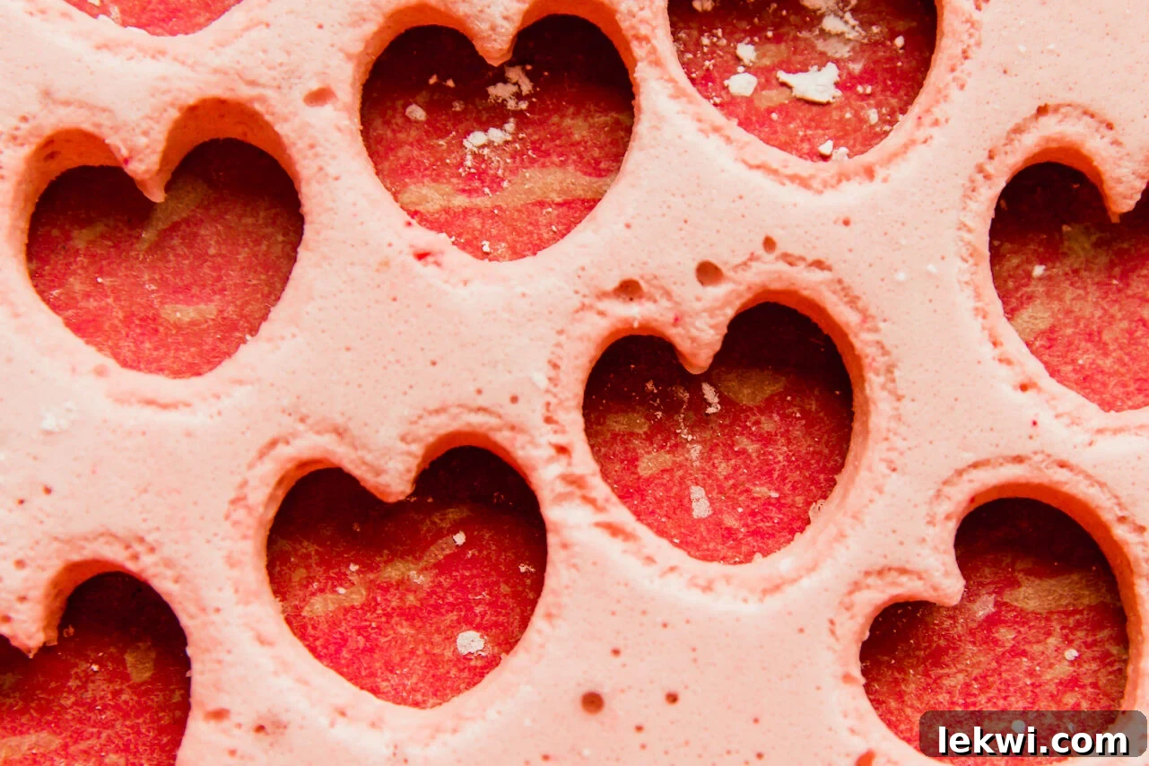 Several small, perfectly cut heart-shaped pink marshmallows artfully arranged on a plate, showcasing their soft, fluffy texture and vibrant color, ready for serving.