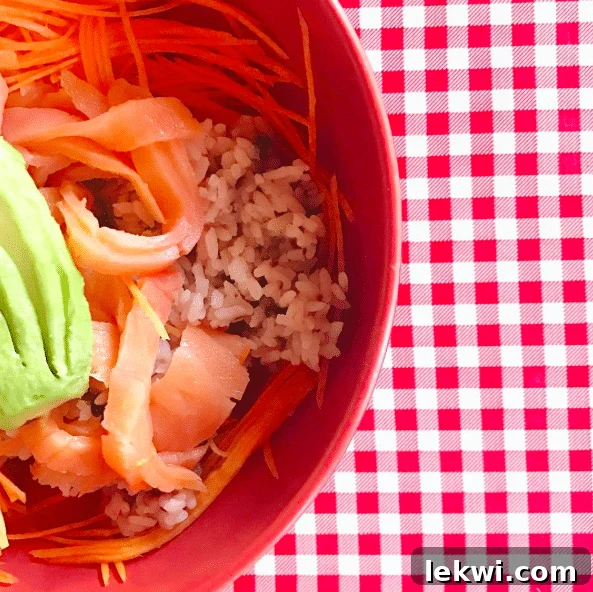 A bowl with rice, slices of tomato, and shredded carrots, carefully prepared.