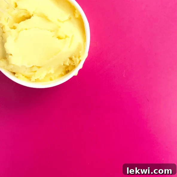 A cup of refreshing mango sorbet on a pink background.