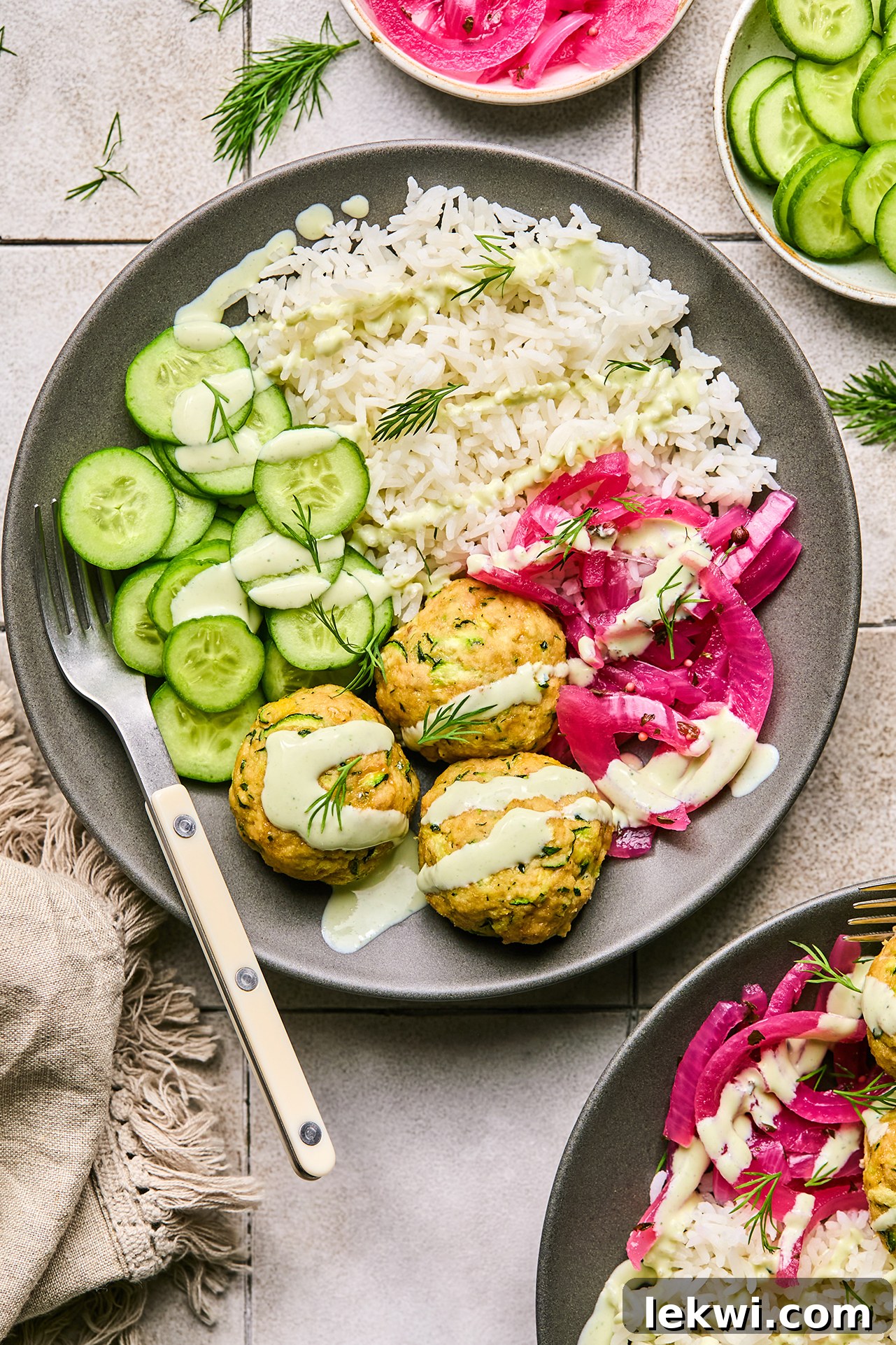 turkey feta meatballs in a bowl with cucumber, rice, and pickled onion, topped yogurt sauce