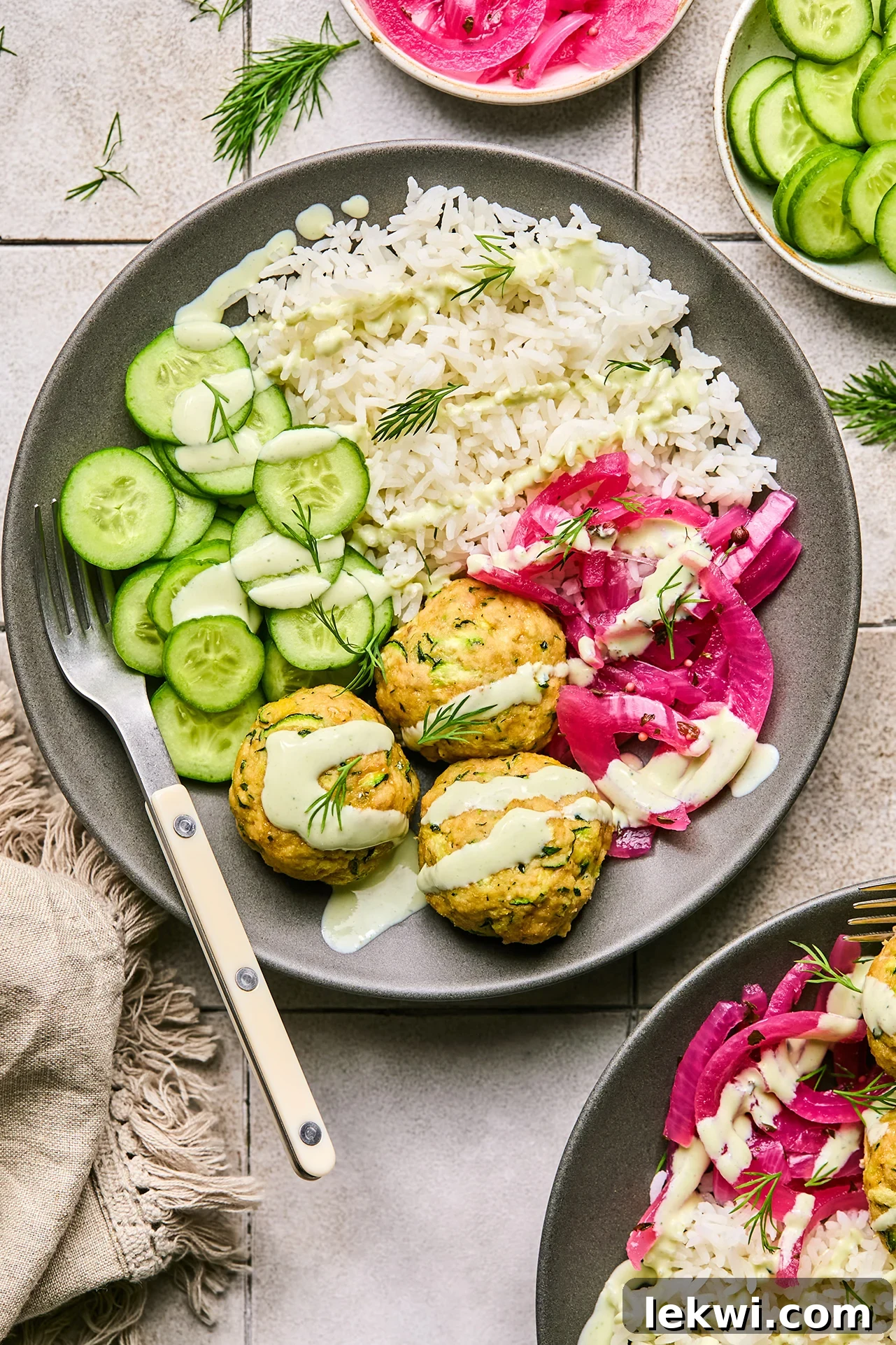 Turkey and feta meatballs served in a bowl with rice, cucumber and pickled onion.