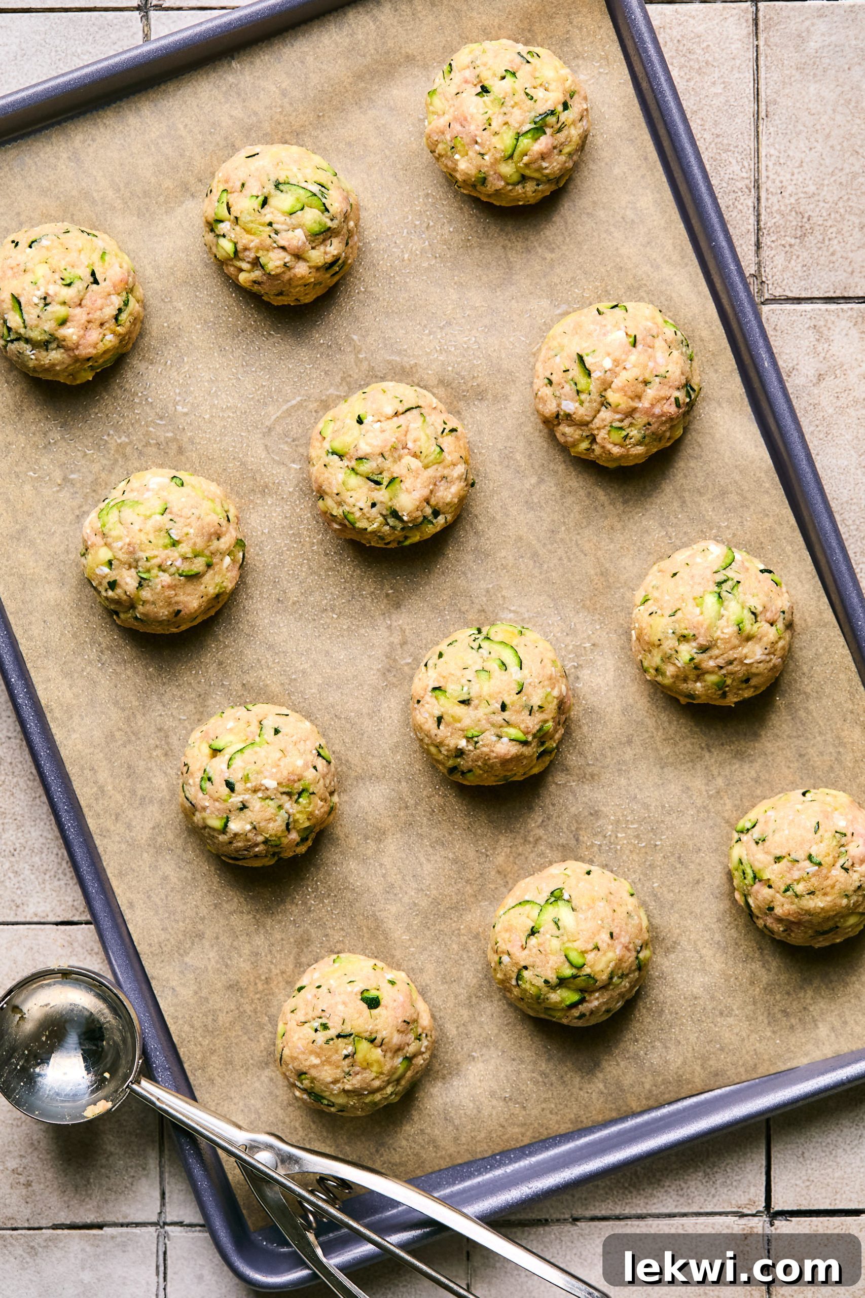 uncooked turkey feta meatballs arranged on a parchment lined baking sheet, ready for the oven