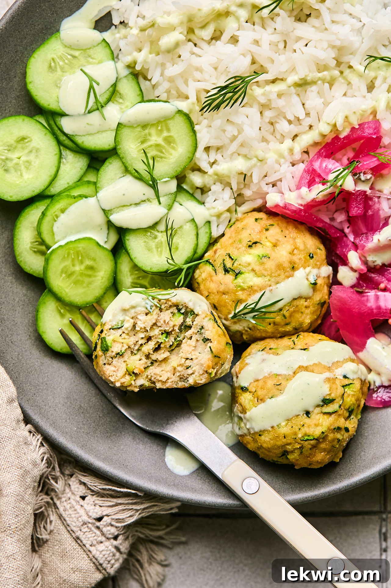 turkey feta meatballs with cucumber, rice, and pickled onion, topped with yogurt sauce, beautifully plated