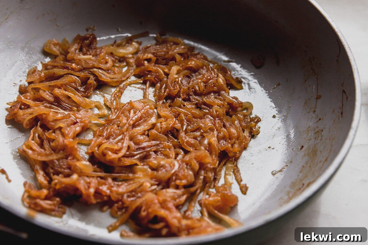 Deeply caramelized golden-brown onions in a skillet, having cooked down and absorbed the savory liquids.