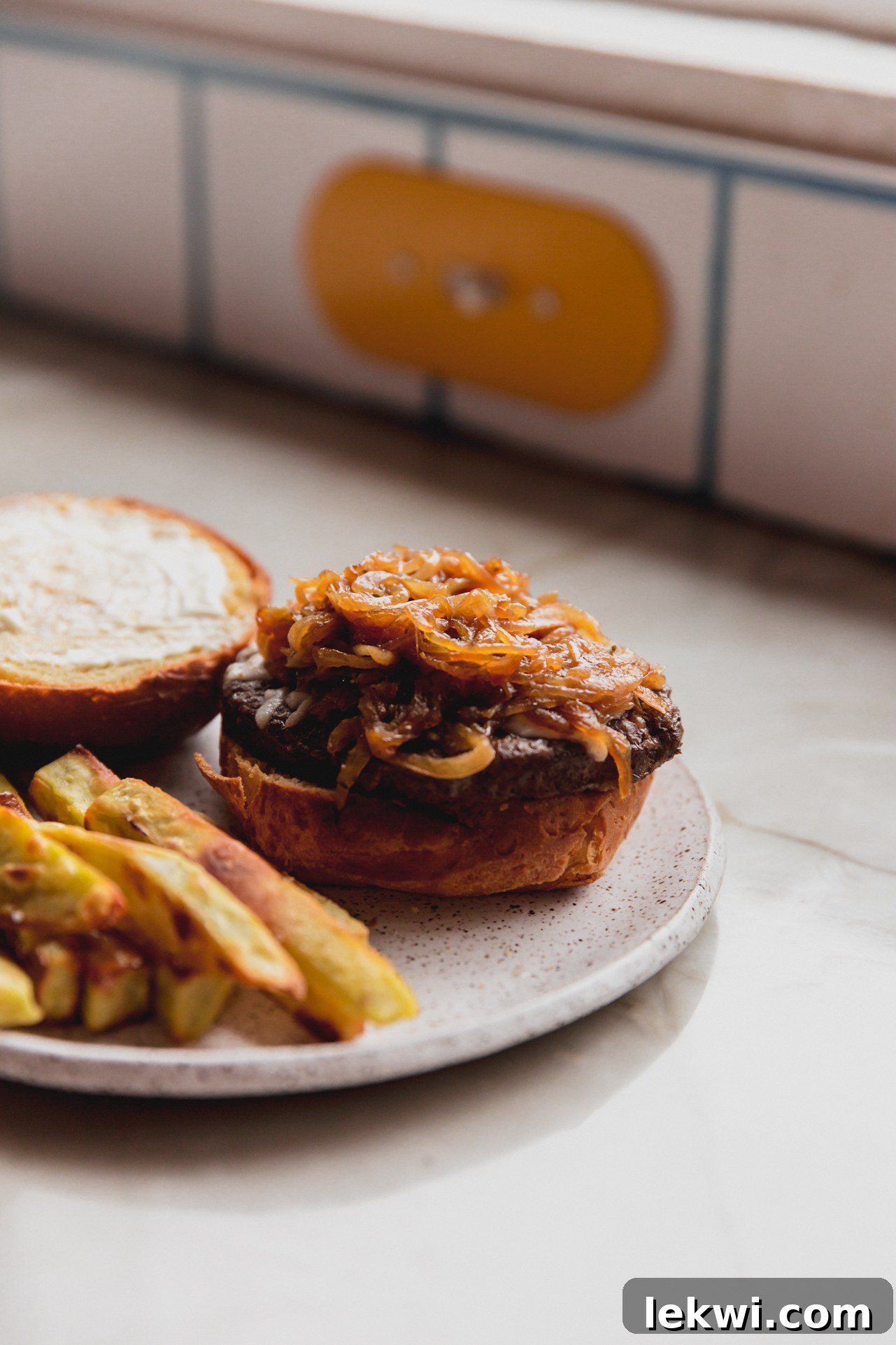 A French Onion Burger perfectly presented on a plate with a side of golden, crispy fries, ready to be enjoyed.