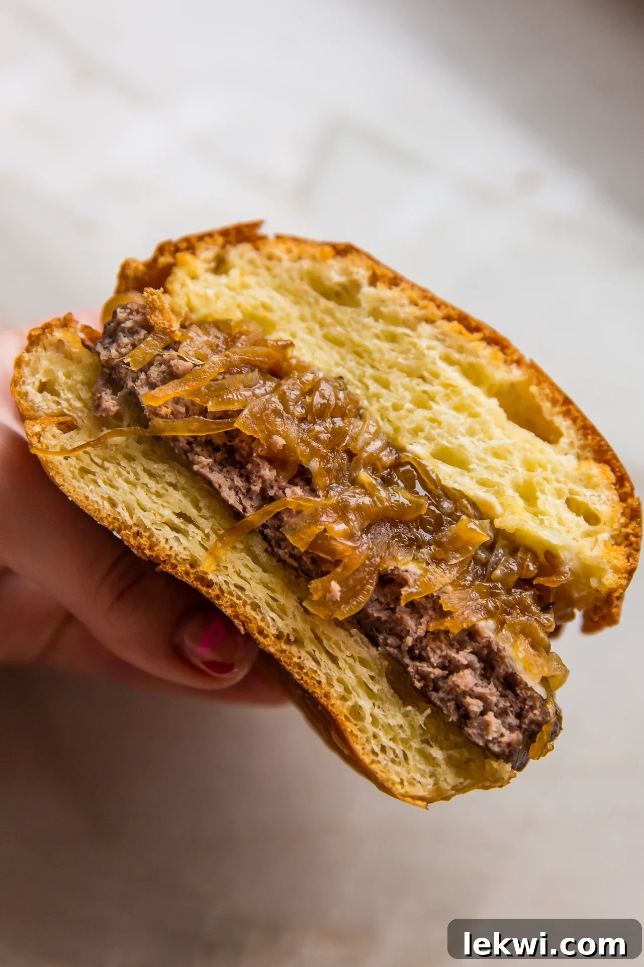 French onion burger sliced in half and being held.