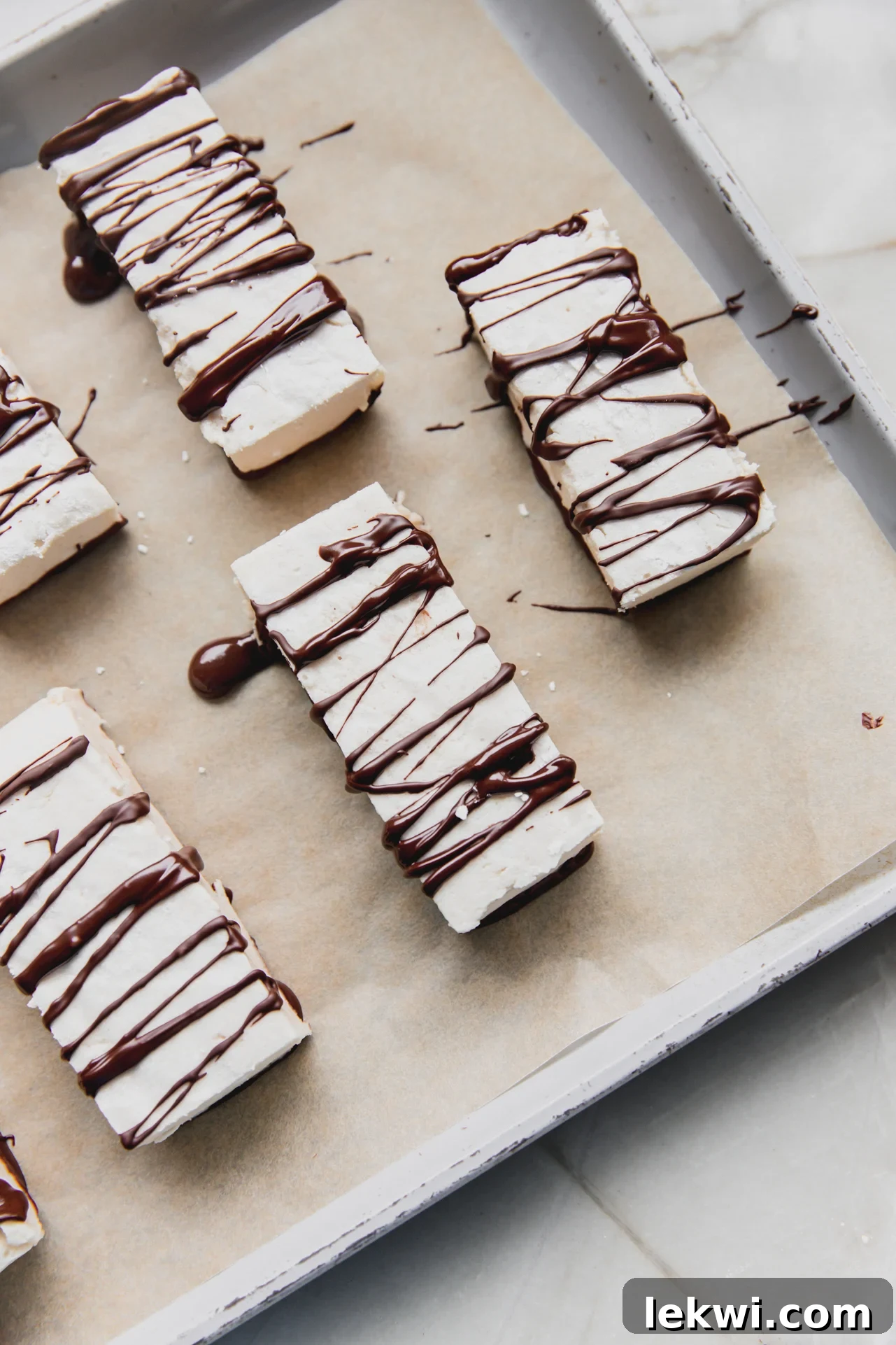 marshmallow protein bars with chocolate drizzle on a parchment lined baking sheet
