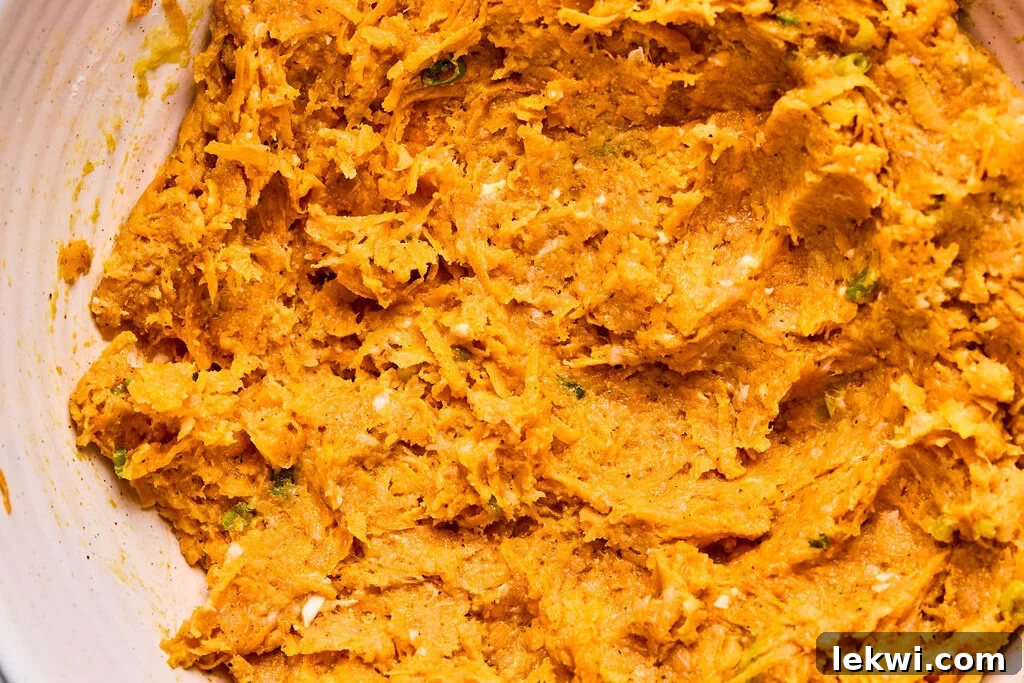 The sweet potato chicken popper mixture is thoroughly combined in a bowl, showcasing the integrated ingredients ready for shaping.