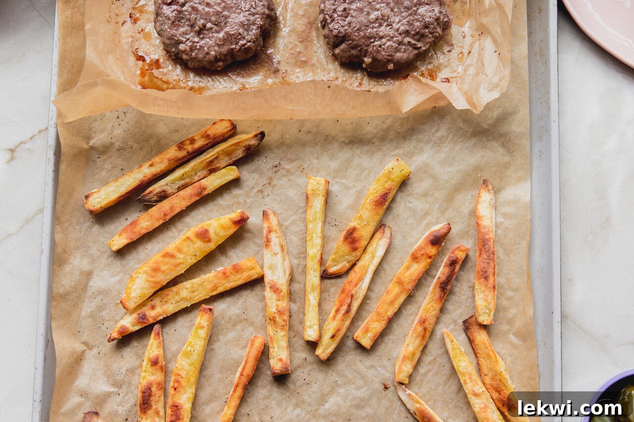 Fully cooked sheet pan burgers and fries, golden and crispy, fresh out of the oven.