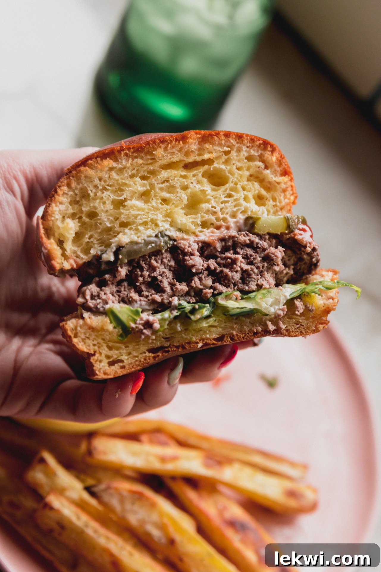 A delicious sheet pan burger served on a bun with fresh toppings, sliced in half to show its juicy interior.
