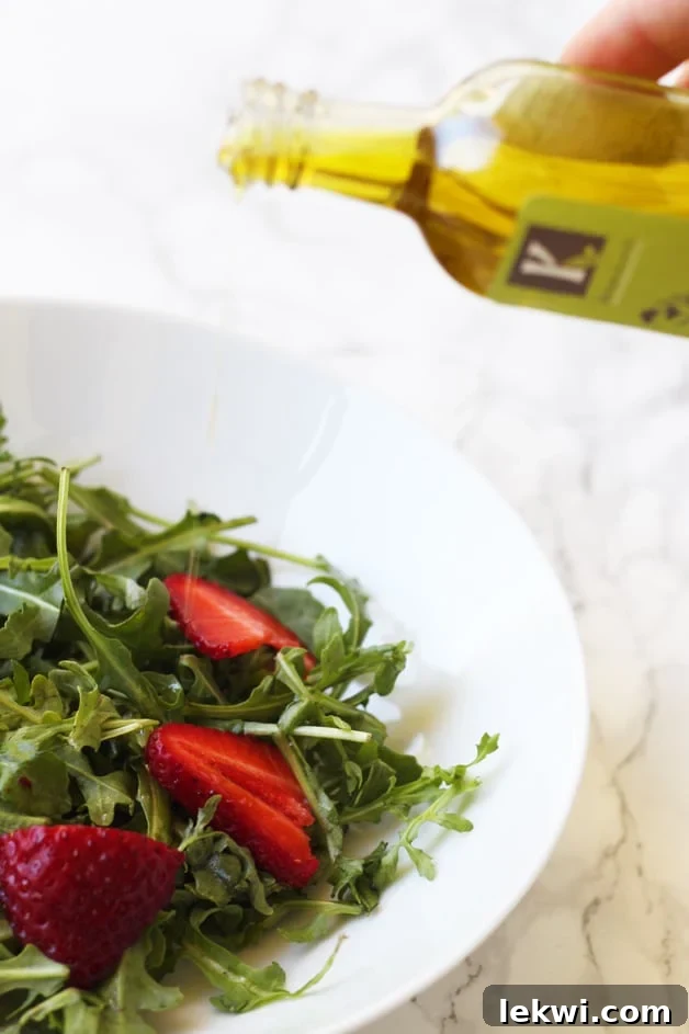 A bottle of olive oil pouring onto a fresh, green salad in a bowl, highlighting its culinary use.