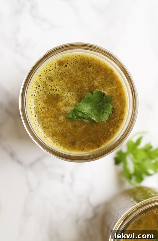 A glass jar filled with vibrant green bone broth drink, ready for consumption.