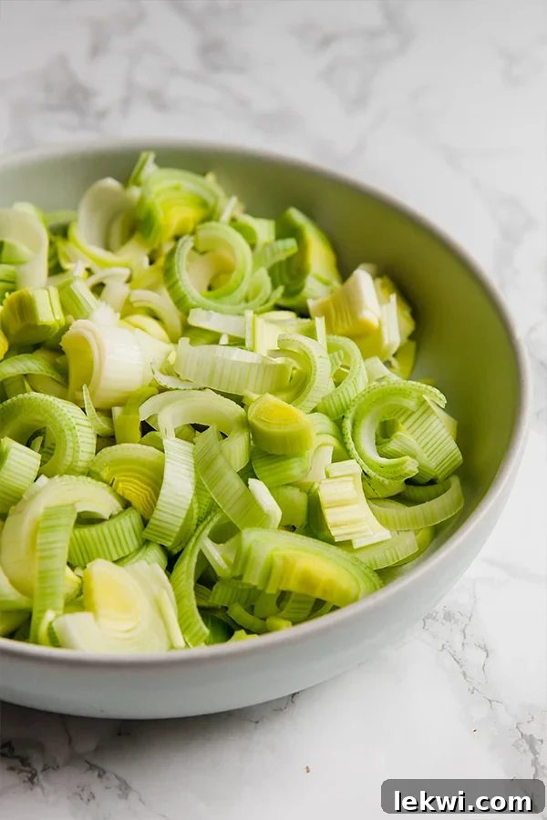 A ceramic bowl filled with prepped leeks to make carrot leek soup.