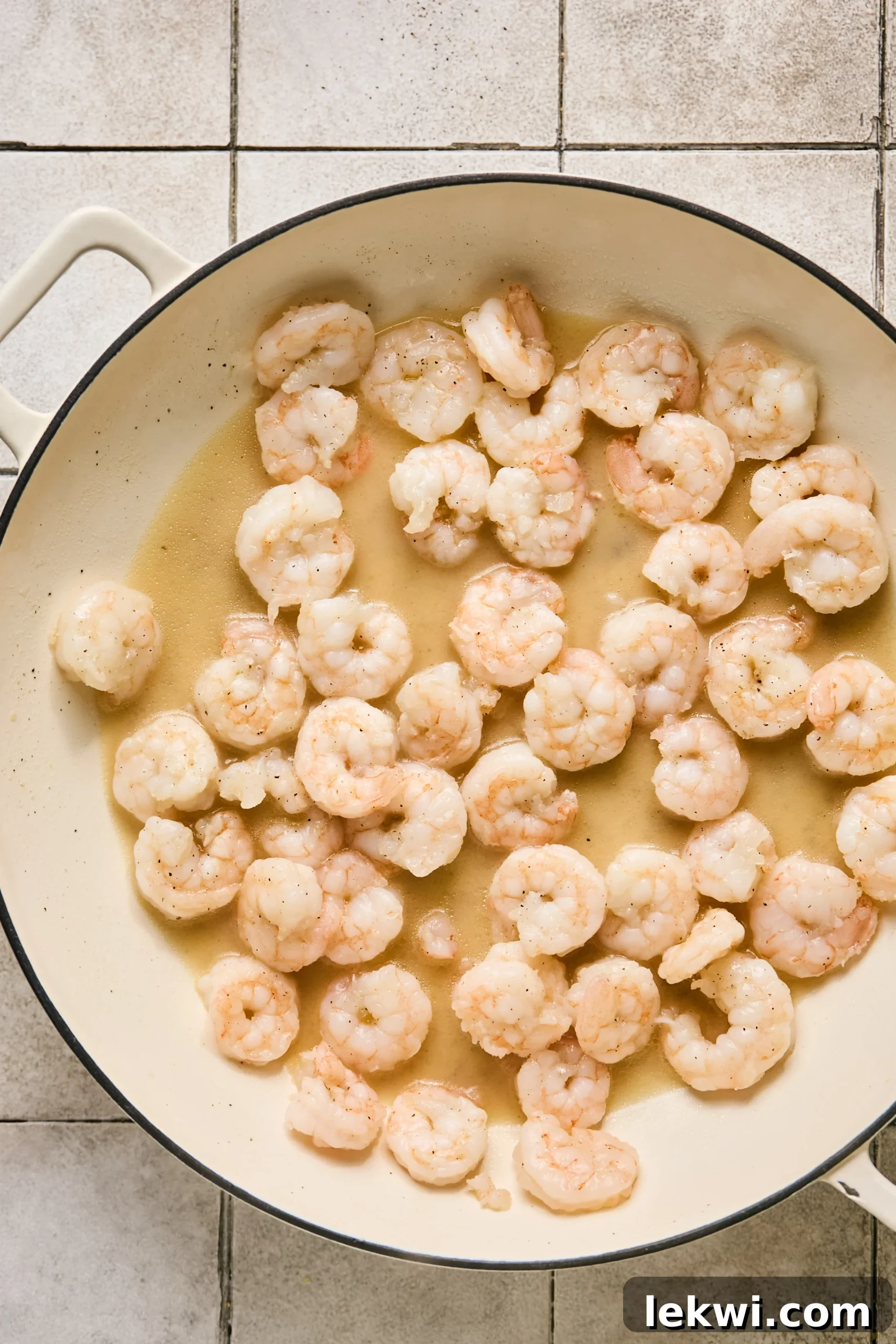 Perfectly cooked, opaque pink shrimp gently resting in a pan with melted ghee, having just been seared.