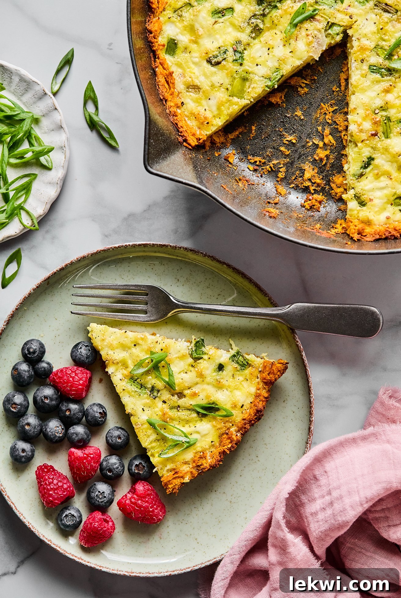 Sweet potato quiche on a green plate served with berries, with a fork on the plate. A healthy and delicious brunch option.