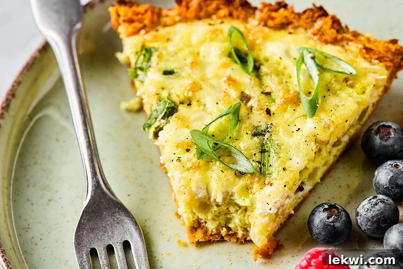 A delicious slice of sweet potato quiche with a bite taken out, served with fresh berries on the side.