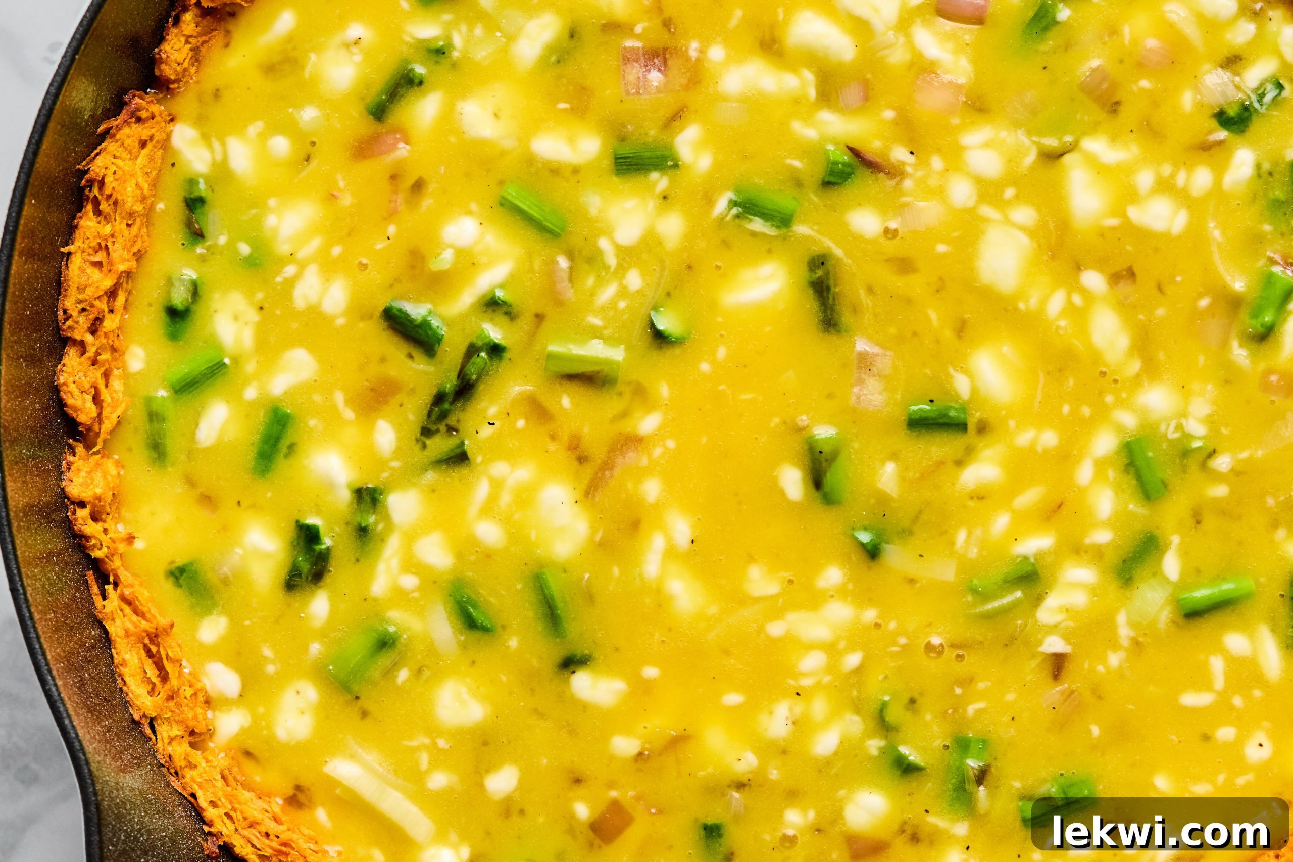 The egg and vegetable mixture being poured into the pre-baked sweet potato crust.