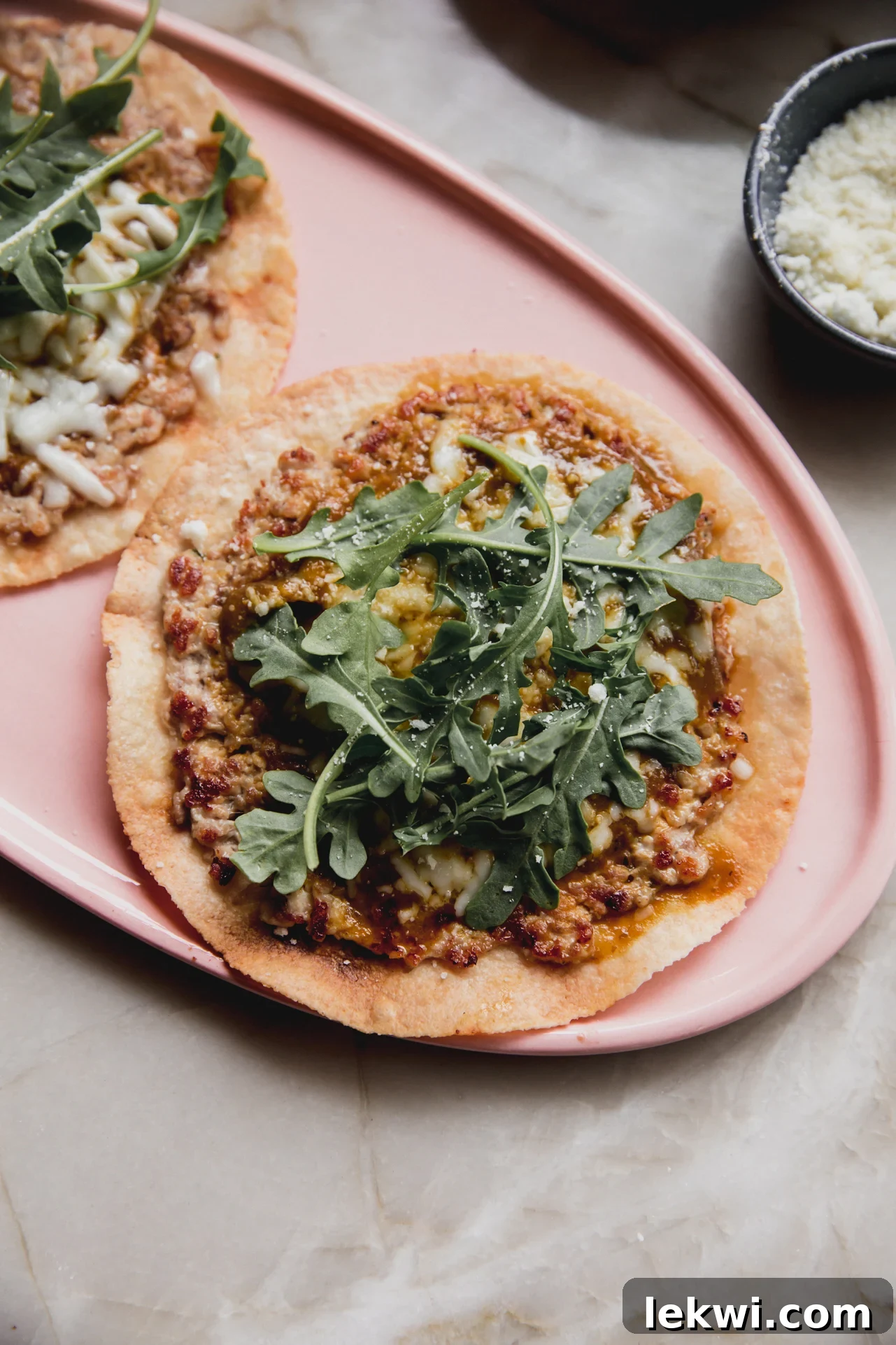 Chicken parm taco on a plate topped with fresh arugula.