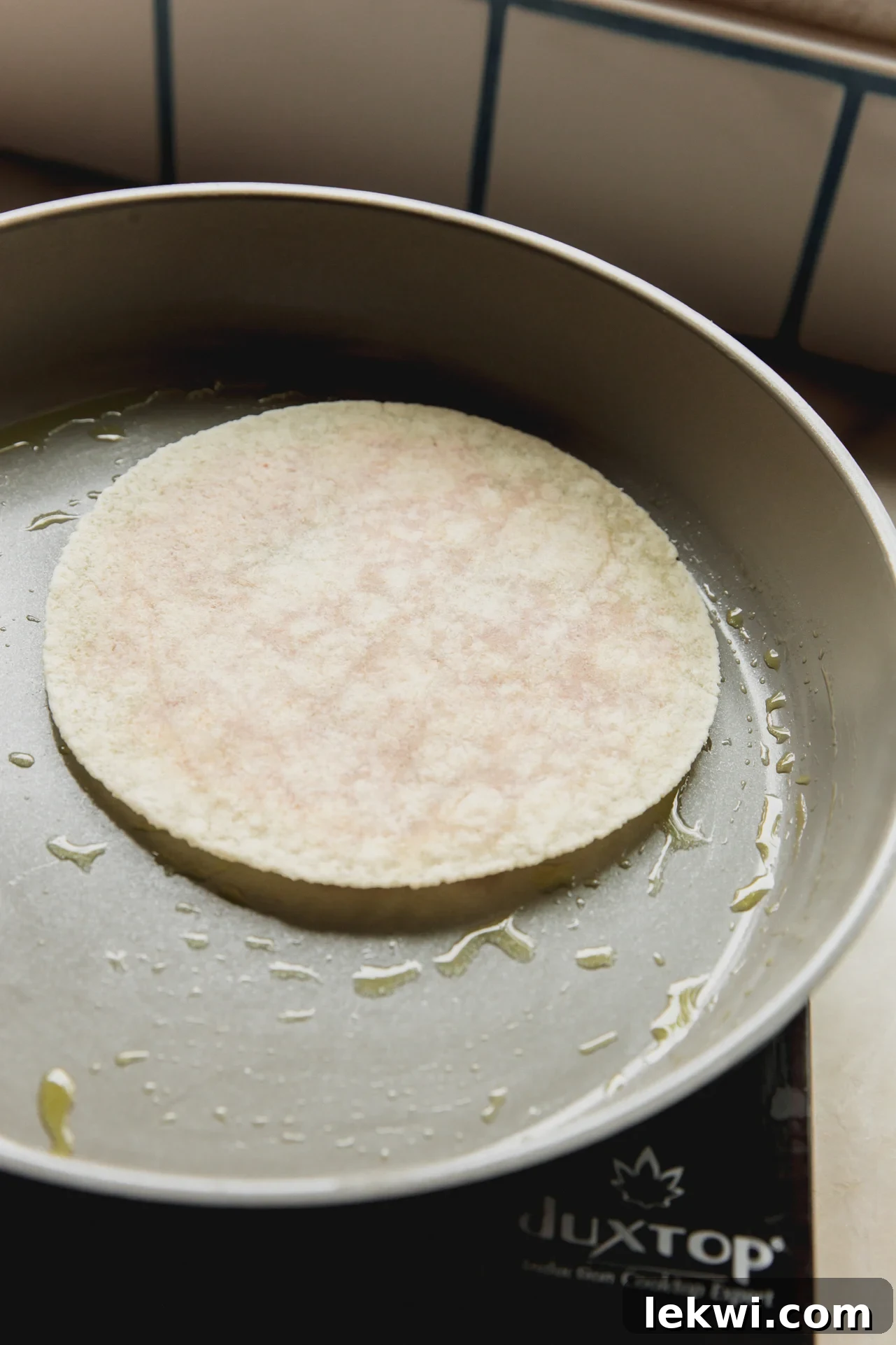 A chicken parm smash burger taco cooking meat-side down in a hot pan, crisping up the chicken.