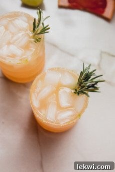 Two beautifully garnished grapefruit paloma mocktails with rosemary sprigs, ready to be enjoyed.