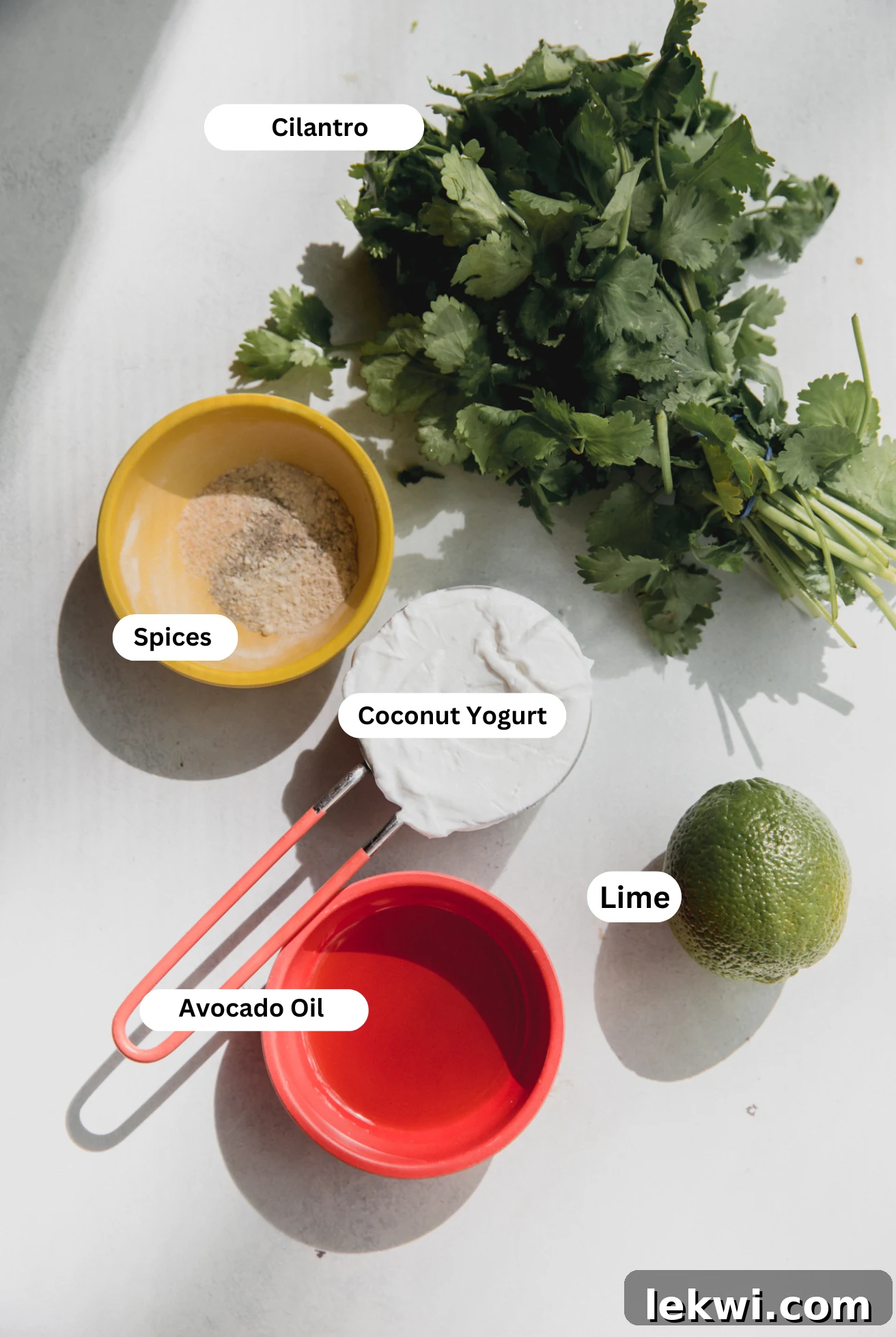 All the fresh ingredients laid out on a table, including coconut yogurt, cilantro, lime, and various spices, ready for making homemade taco salad dressing.
