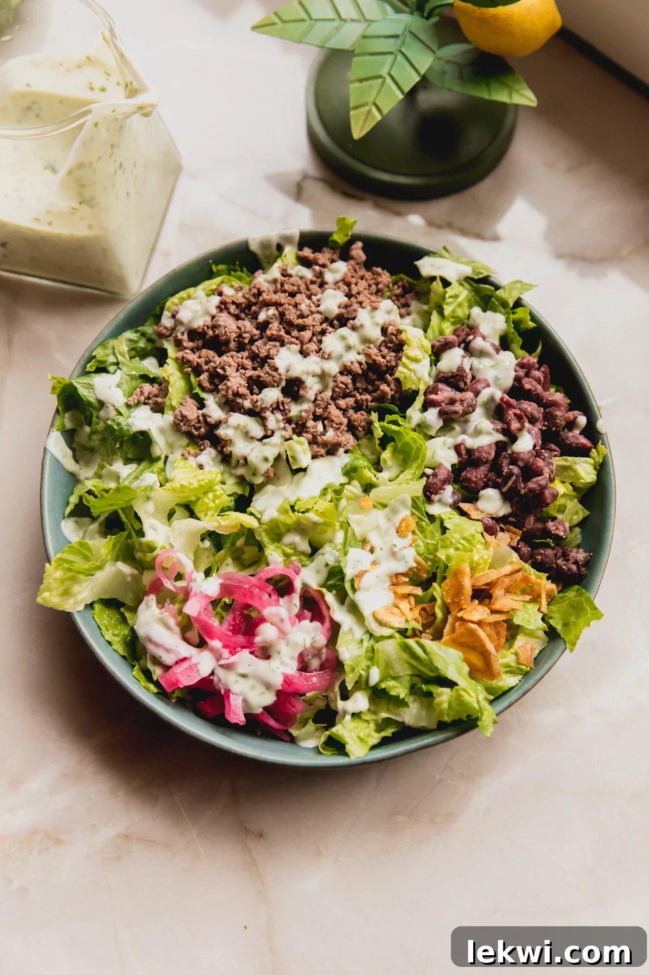 A vibrant and colorful taco salad, beautifully arranged in a bowl, with a generous drizzle of homemade taco salad dressing on top, ready to be enjoyed.