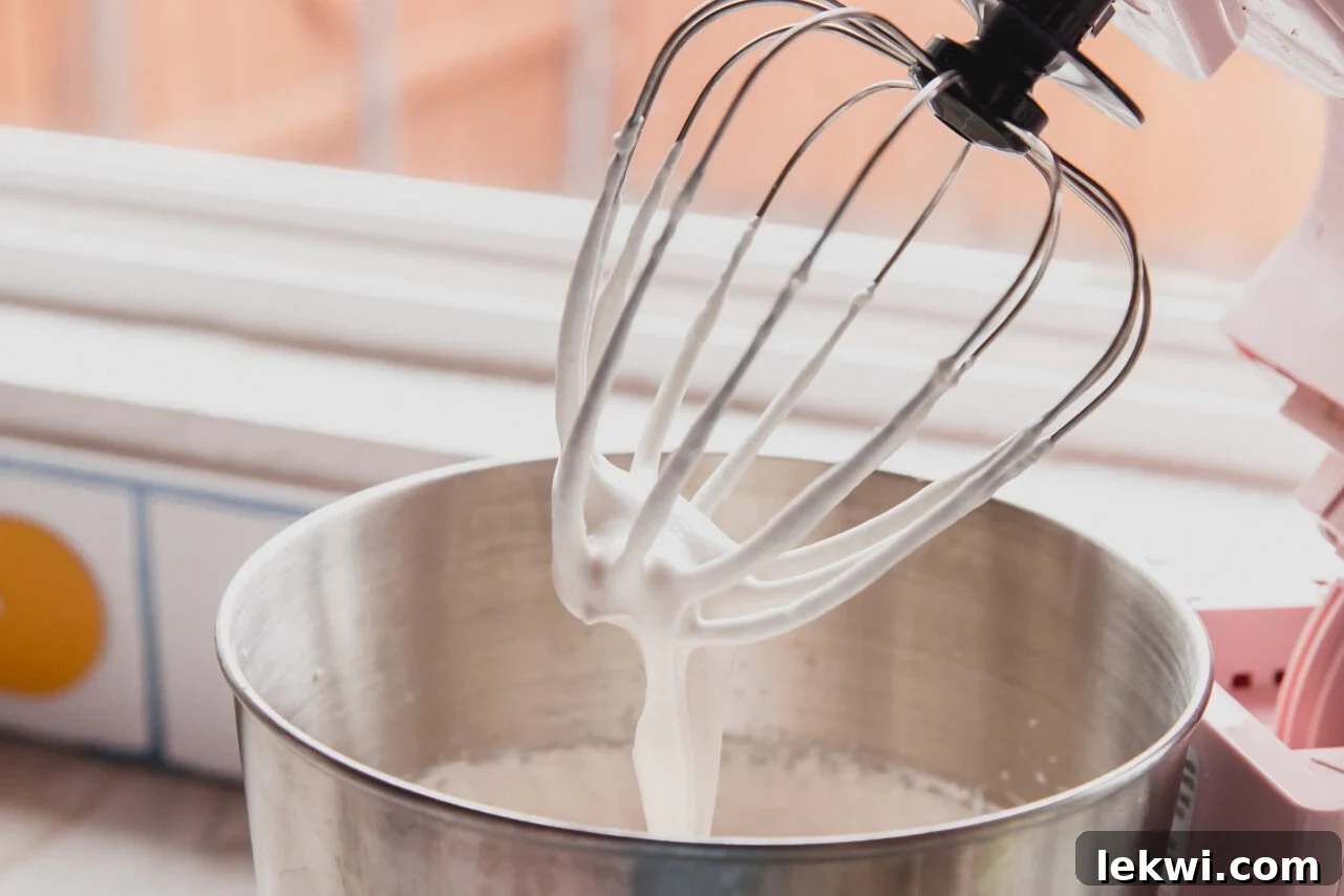 A stand mixer after making the marshmallow layer, showing thick, whipped marshmallow.