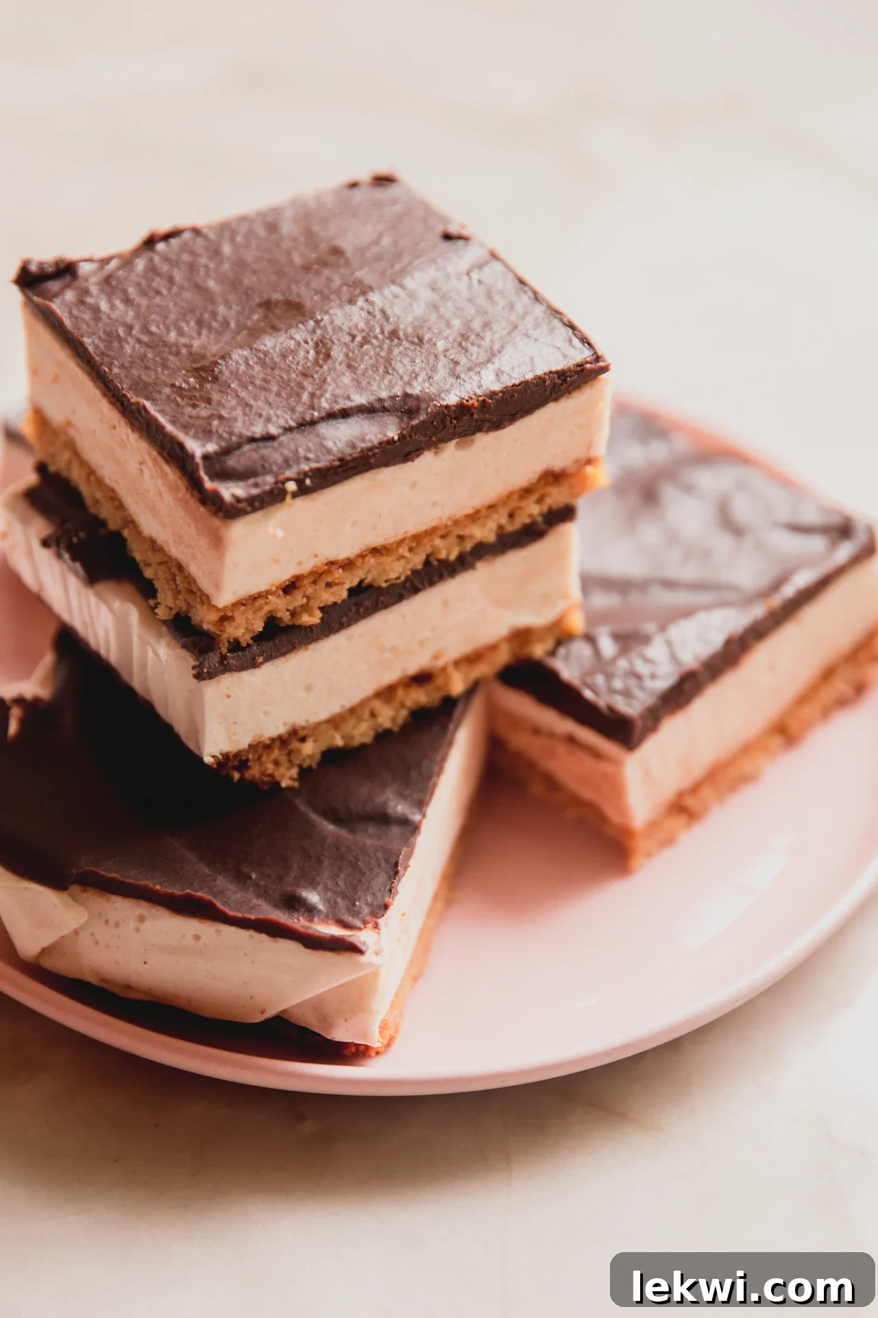 Protein s'mores bars sliced and stacked on a pink plate, showing the layers clearly.