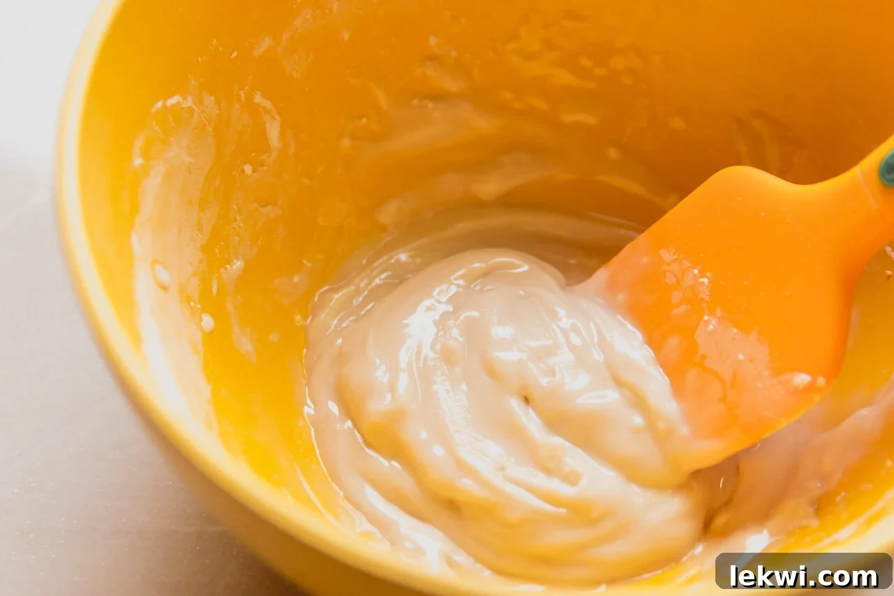 A bowl of powdered sugar, water, and vanilla extract mixed together to form a thick, smooth paste.