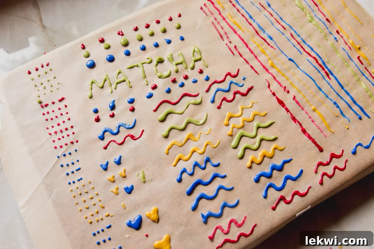 A sheet of parchment paper covered with neat, colorful lines of icing, laid out to dry.