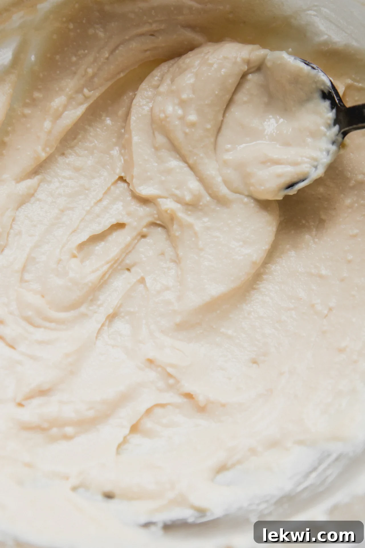 A spoon smoothing out the perfectly mixed cannoli cream, demonstrating its creamy and airy texture.