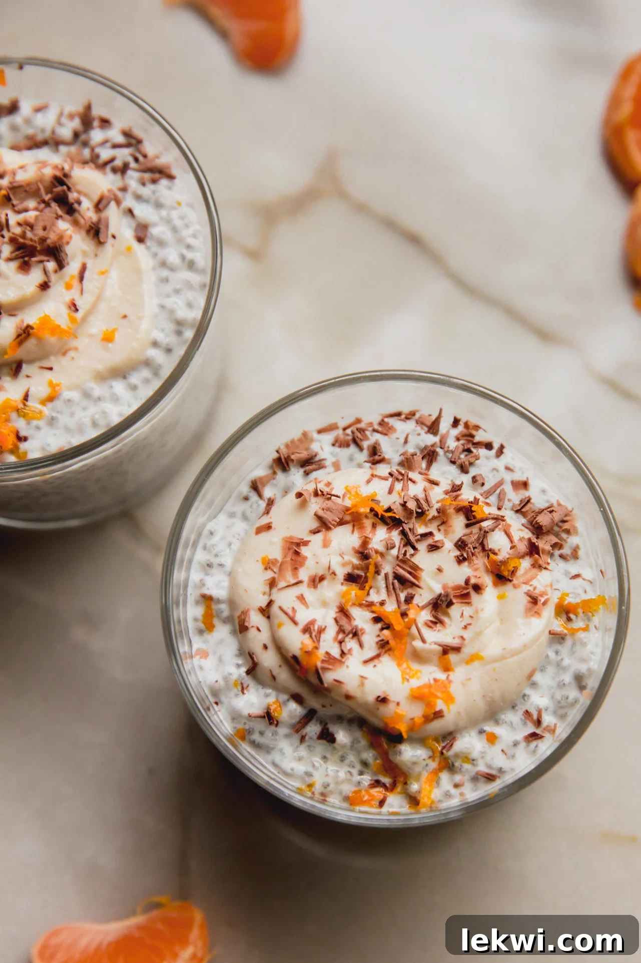 Two aesthetically pleasing cups of cannoli chia seed pudding, garnished and ready, placed on a kitchen counter.